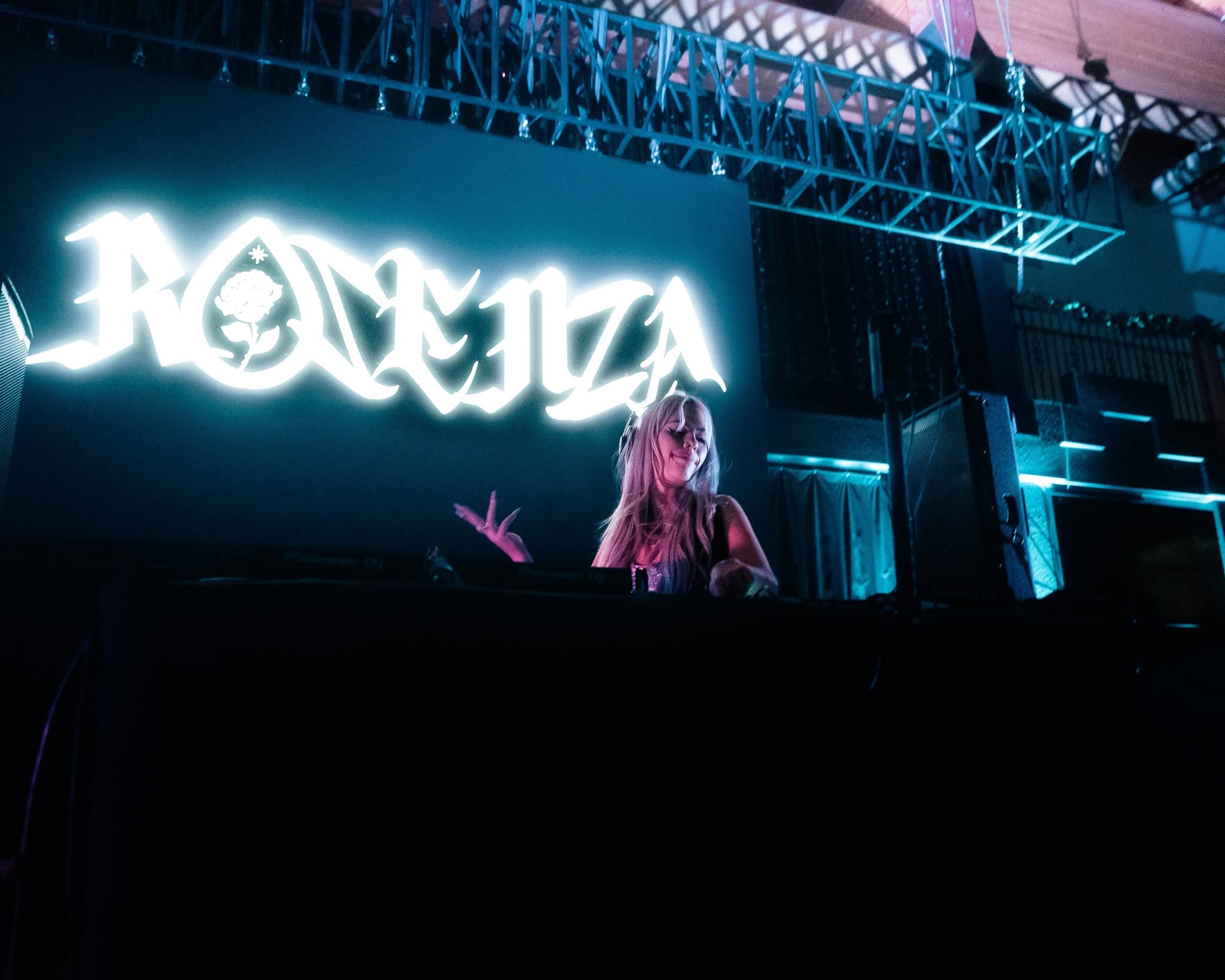 ROZENZA at the decks beneath a giant glowing ROZENZA logo on a teal-lit stage