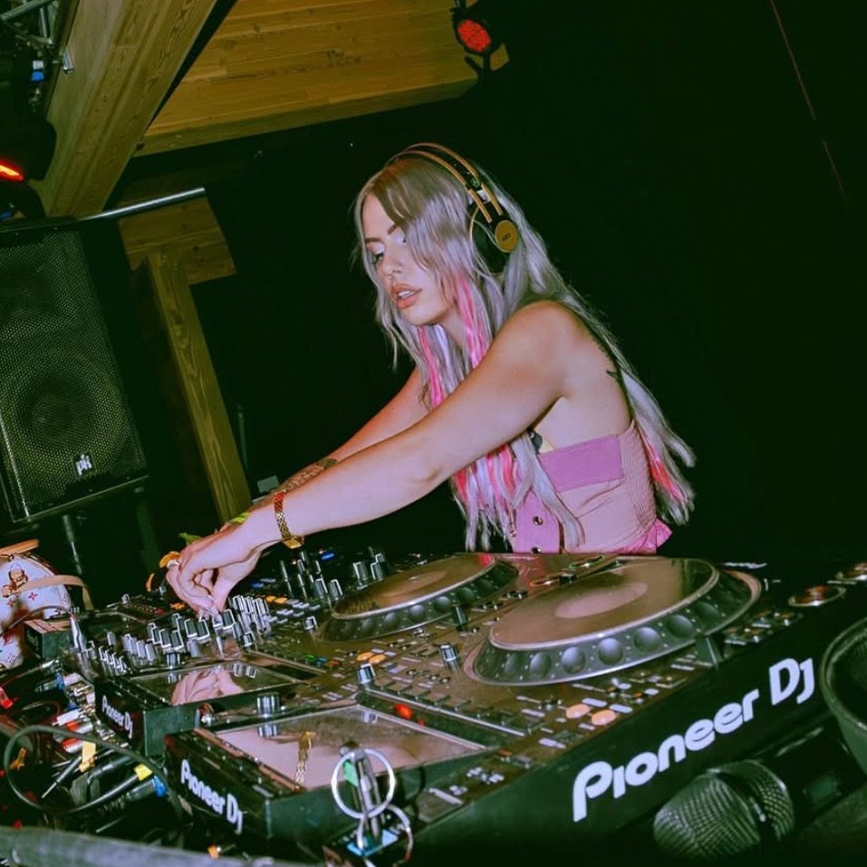 ROZENZA mixing on Pioneer DJ decks and a mixer, headphones on, in a dark club