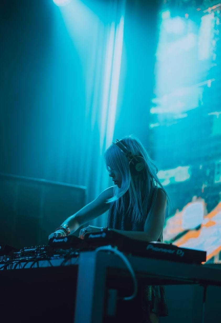 ROZENZA DJing on Pioneer CDJs under teal blue stage lights